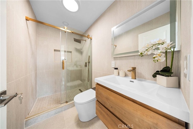 bathroom with a shower with door, tile walls, vanity, tile patterned floors, and toilet