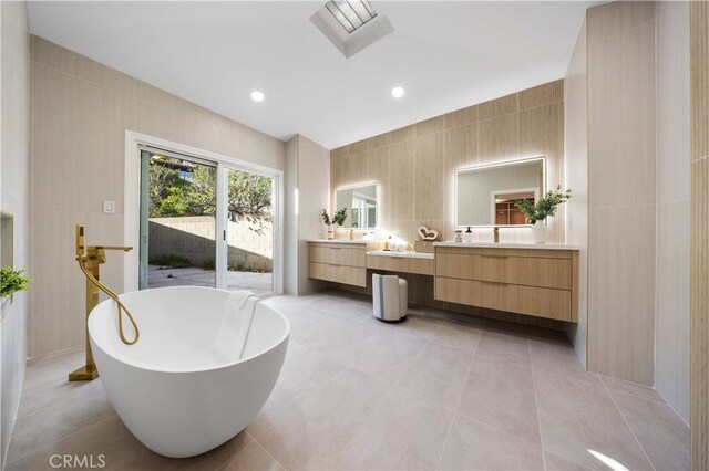 bathroom featuring vanity, tile walls, tile patterned floors, and a bathtub