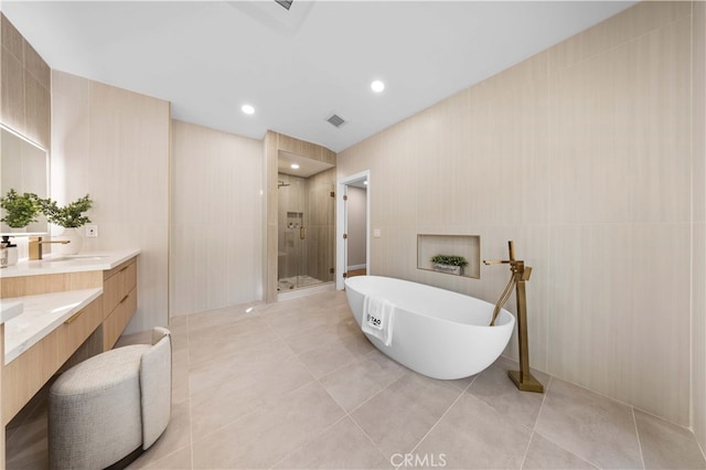 bathroom featuring tile patterned floors, plus walk in shower, tile walls, and vanity