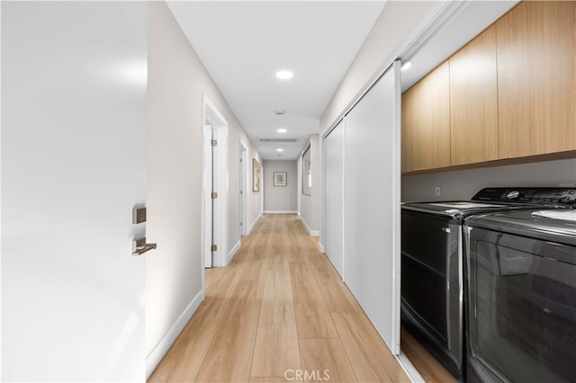 washroom featuring cabinets, washing machine and clothes dryer, and light wood-type flooring