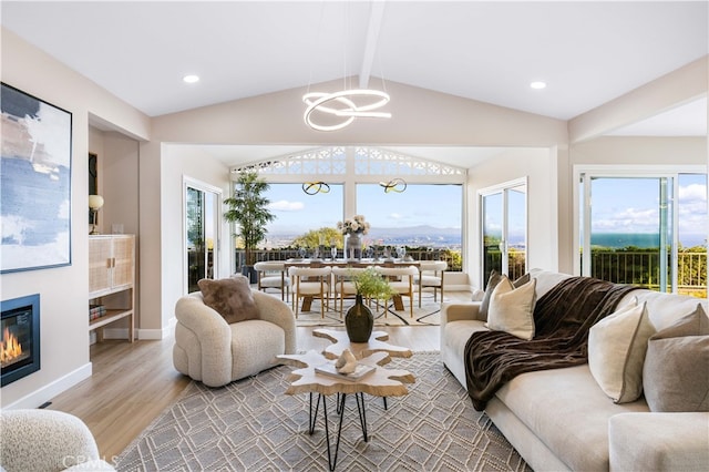 living room with an inviting chandelier, plenty of natural light, light hardwood / wood-style floors, and lofted ceiling with beams