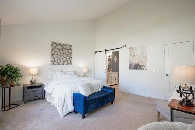 carpeted bedroom with a barn door, high vaulted ceiling, and ensuite bath