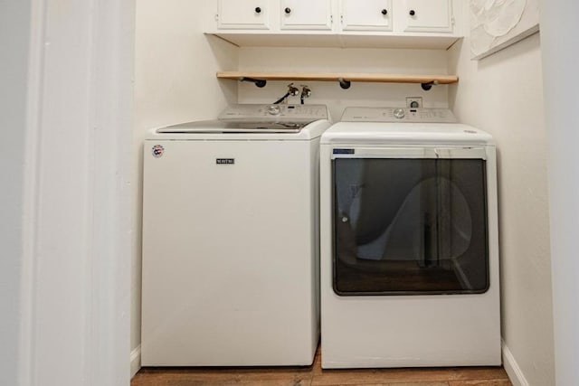 clothes washing area featuring cabinets, hardwood / wood-style flooring, and independent washer and dryer