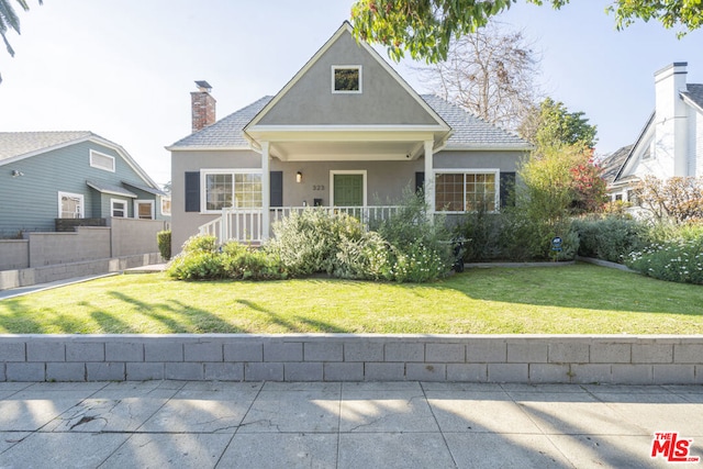 front facade featuring covered porch and a front yard