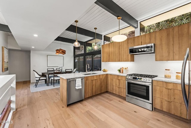 kitchen featuring sink, decorative light fixtures, appliances with stainless steel finishes, light hardwood / wood-style floors, and backsplash