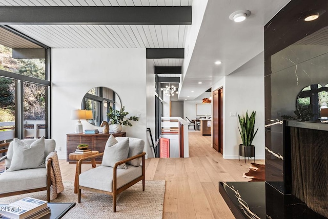 sitting room featuring beamed ceiling, floor to ceiling windows, a chandelier, and light wood-type flooring