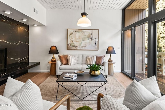 living room with a premium fireplace, a wall of windows, and light hardwood / wood-style floors