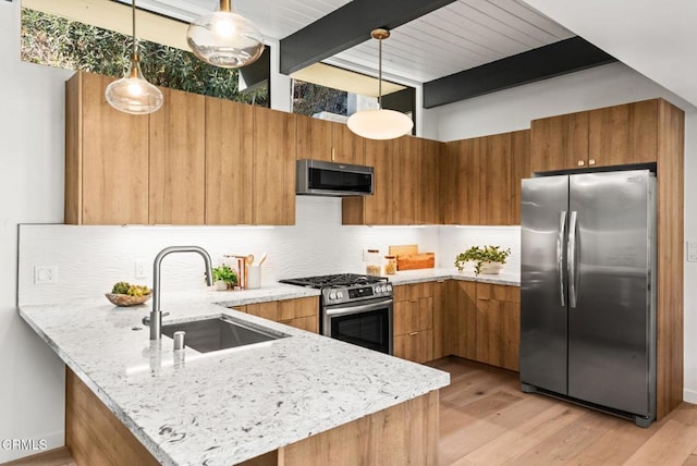 kitchen with stainless steel appliances, kitchen peninsula, sink, and hanging light fixtures