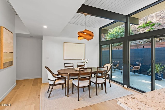 dining room with vaulted ceiling with beams and light hardwood / wood-style flooring