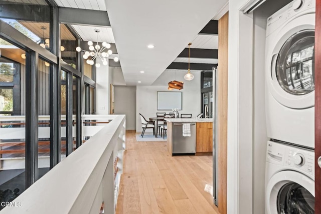 corridor with beamed ceiling, stacked washer / dryer, light hardwood / wood-style floors, and a notable chandelier