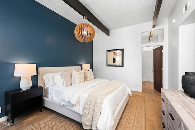 bedroom with beam ceiling and light hardwood / wood-style flooring