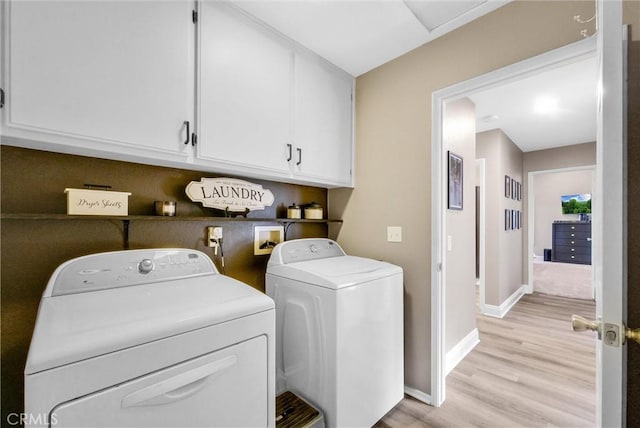 laundry area featuring cabinets, washer and clothes dryer, and light wood-type flooring