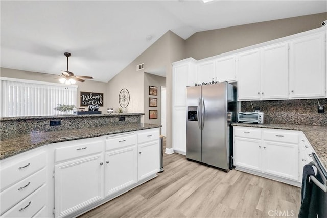 kitchen featuring lofted ceiling, dark stone countertops, stainless steel refrigerator with ice dispenser, white cabinets, and light wood-type flooring