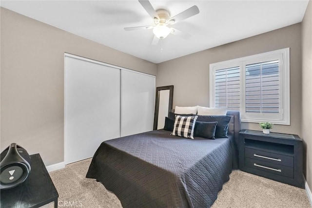 bedroom featuring light carpet, ceiling fan, and a closet