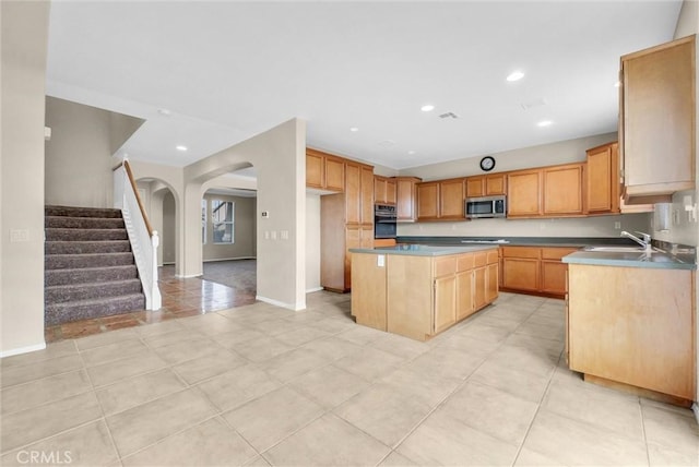 kitchen with a kitchen island, sink, oven, light tile patterned floors, and cooktop