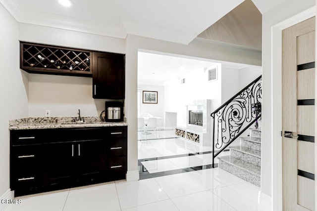 bar featuring ornamental molding, sink, light tile patterned floors, and light stone counters