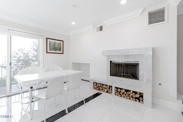 dining area with a tiled fireplace, ornamental molding, and light tile patterned flooring