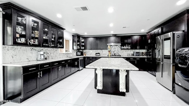 kitchen featuring a kitchen island, tasteful backsplash, sink, light tile patterned floors, and wall chimney range hood