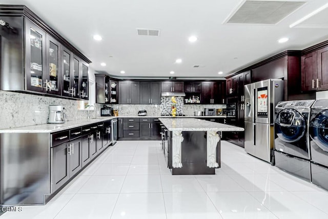 kitchen with light tile patterned flooring, separate washer and dryer, light stone counters, and stainless steel refrigerator