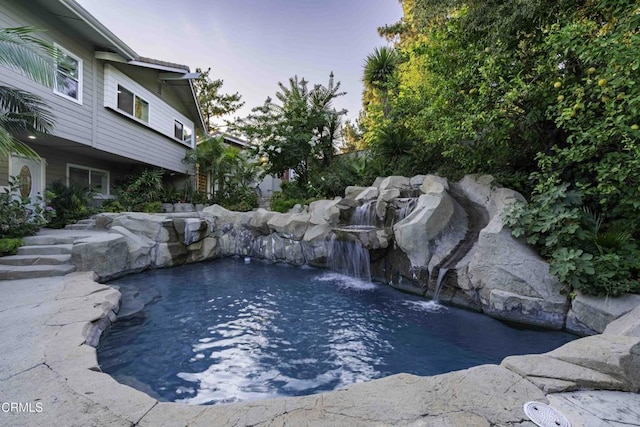 pool at dusk with pool water feature