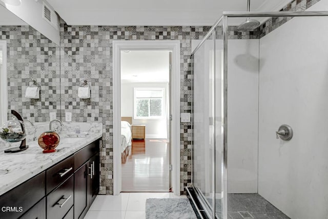 bathroom featuring vanity, tile patterned flooring, a shower with door, and tile walls