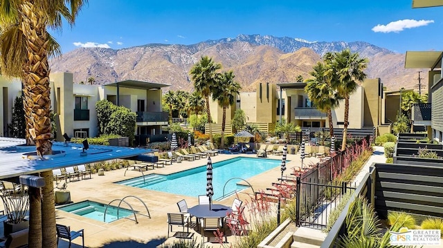 view of swimming pool with a patio, a mountain view, and a community hot tub