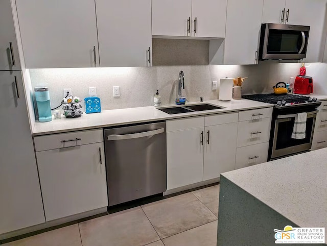 kitchen with sink, light tile patterned floors, white cabinetry, stainless steel appliances, and decorative backsplash