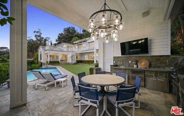 patio terrace at dusk with an outdoor kitchen and a balcony