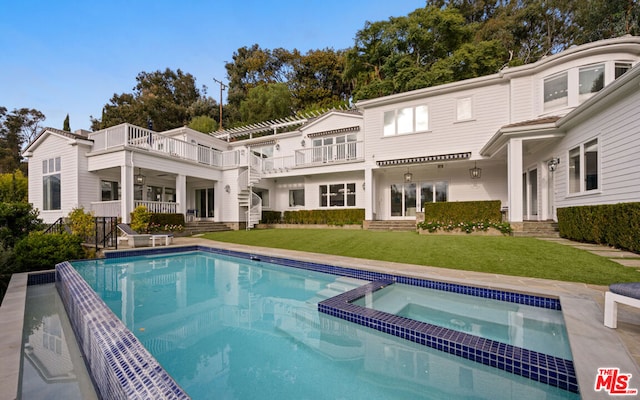 back of house with a balcony, a pergola, a pool with hot tub, and a lawn