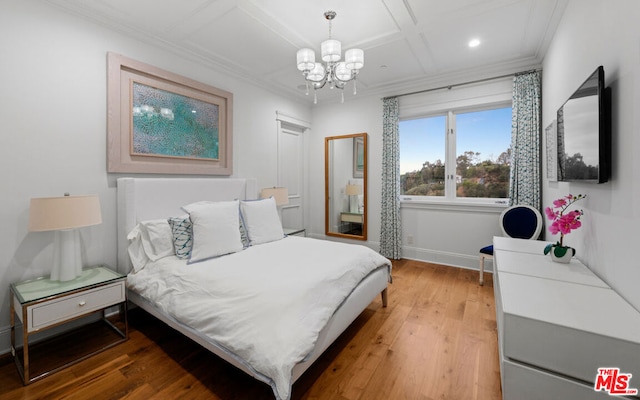 bedroom featuring coffered ceiling, wood-type flooring, ornamental molding, and an inviting chandelier