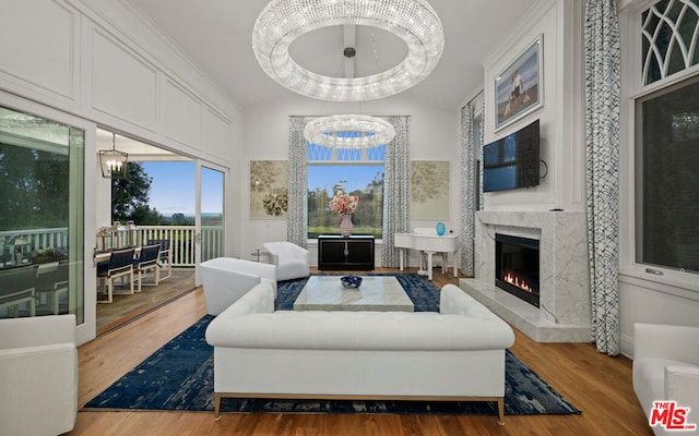 living room featuring lofted ceiling, hardwood / wood-style floors, a fireplace, and a chandelier