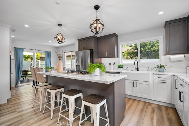 kitchen with a kitchen island, decorative light fixtures, sink, stainless steel appliances, and dark brown cabinets