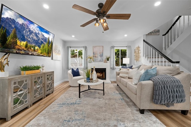 living room featuring hardwood / wood-style floors, a wealth of natural light, a brick fireplace, and ceiling fan