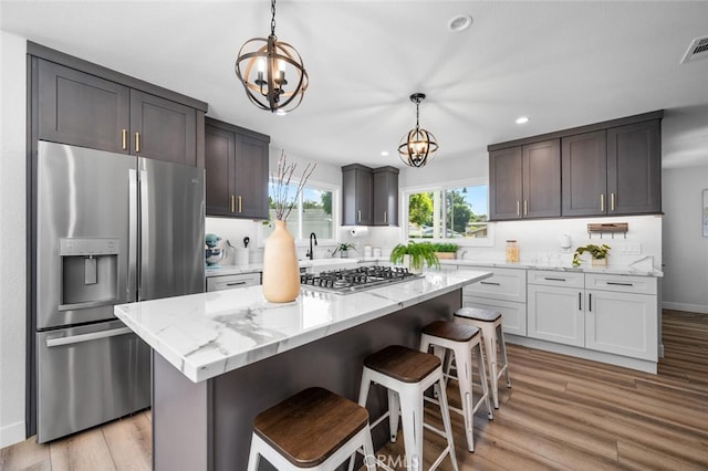 kitchen featuring hanging light fixtures, stainless steel appliances, light hardwood / wood-style floors, and a kitchen island