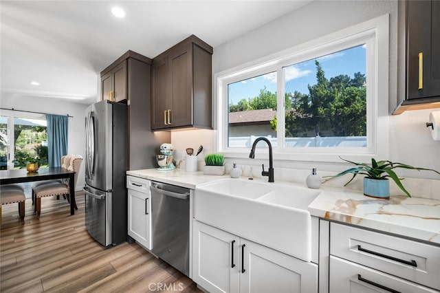 kitchen with sink, white cabinets, dark brown cabinetry, light hardwood / wood-style floors, and stainless steel appliances