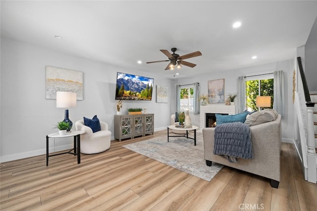 living room featuring hardwood / wood-style floors, a fireplace, and ceiling fan