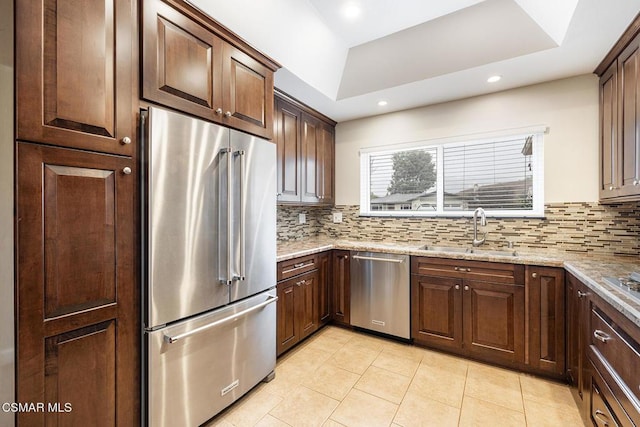 kitchen featuring sink, light tile patterned floors, stainless steel appliances, light stone countertops, and decorative backsplash