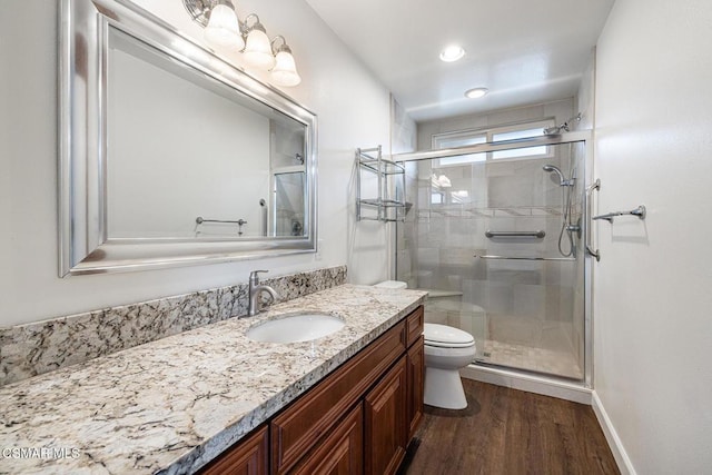 bathroom with vanity, a shower with shower door, toilet, and wood-type flooring