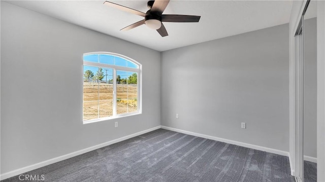 empty room with ceiling fan and dark colored carpet