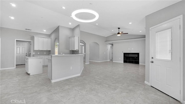 kitchen featuring tasteful backsplash, a center island, vaulted ceiling, ceiling fan, and white cabinets