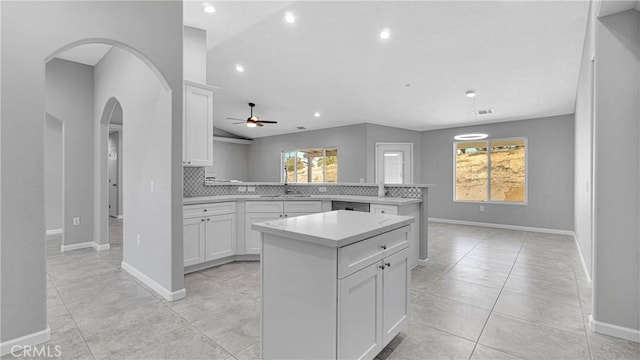 kitchen featuring ceiling fan, white cabinetry, a center island, decorative backsplash, and kitchen peninsula