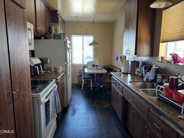 kitchen with pendant lighting, sink, white appliances, backsplash, and dark tile patterned flooring