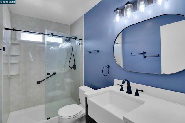 bathroom with a shower with door, vanity, and toilet