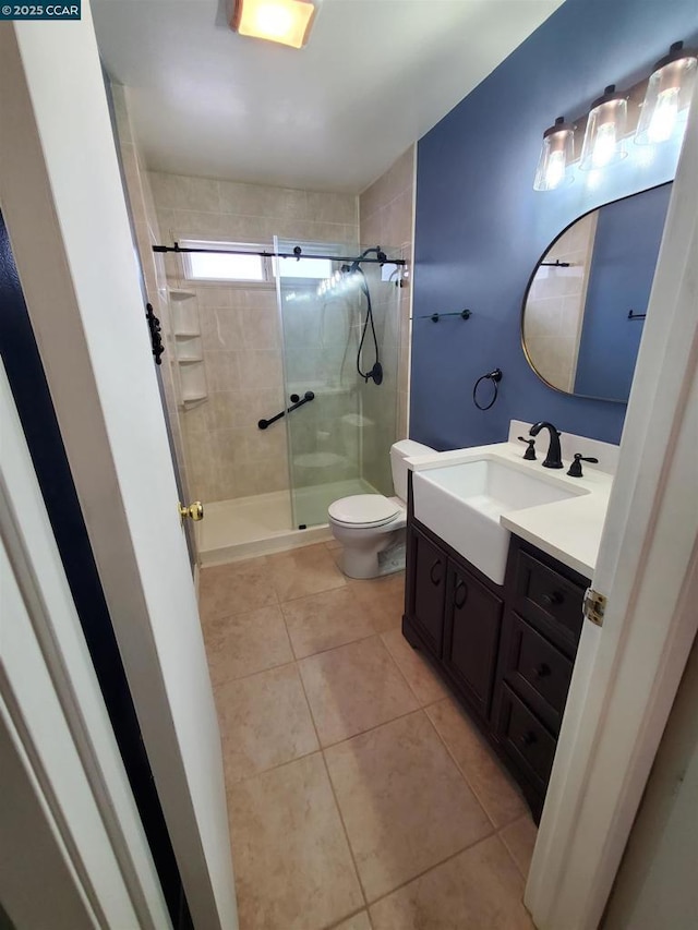 bathroom featuring tile patterned flooring, vanity, toilet, and walk in shower