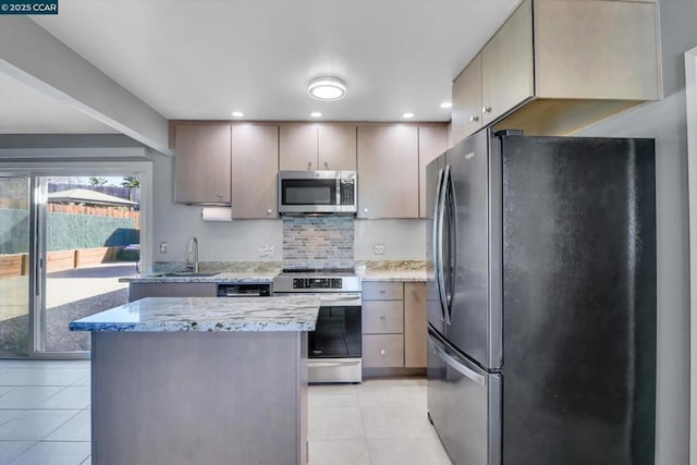 kitchen featuring a kitchen island, appliances with stainless steel finishes, tasteful backsplash, light tile patterned floors, and light stone counters