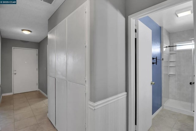 hallway with light tile patterned floors and a textured ceiling