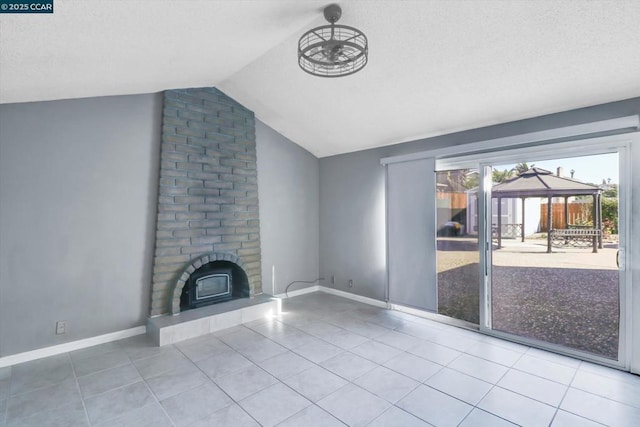 unfurnished living room featuring vaulted ceiling, a brick fireplace, and tile patterned floors