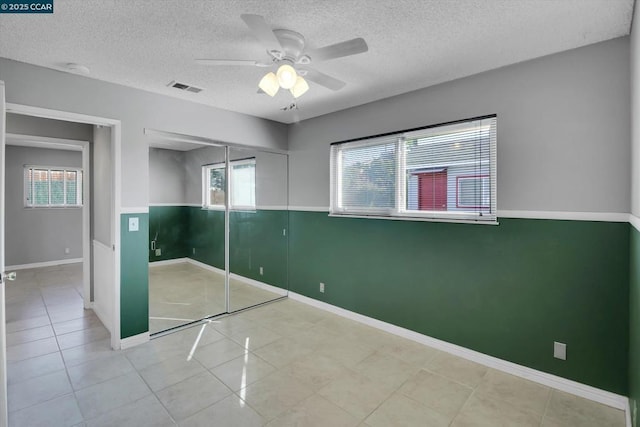 unfurnished bedroom with a textured ceiling, a closet, ceiling fan, and light tile patterned flooring