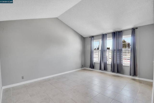 tiled spare room with lofted ceiling and a textured ceiling