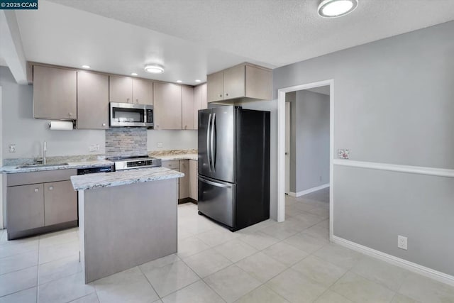 kitchen featuring sink, a center island, a textured ceiling, light tile patterned floors, and appliances with stainless steel finishes